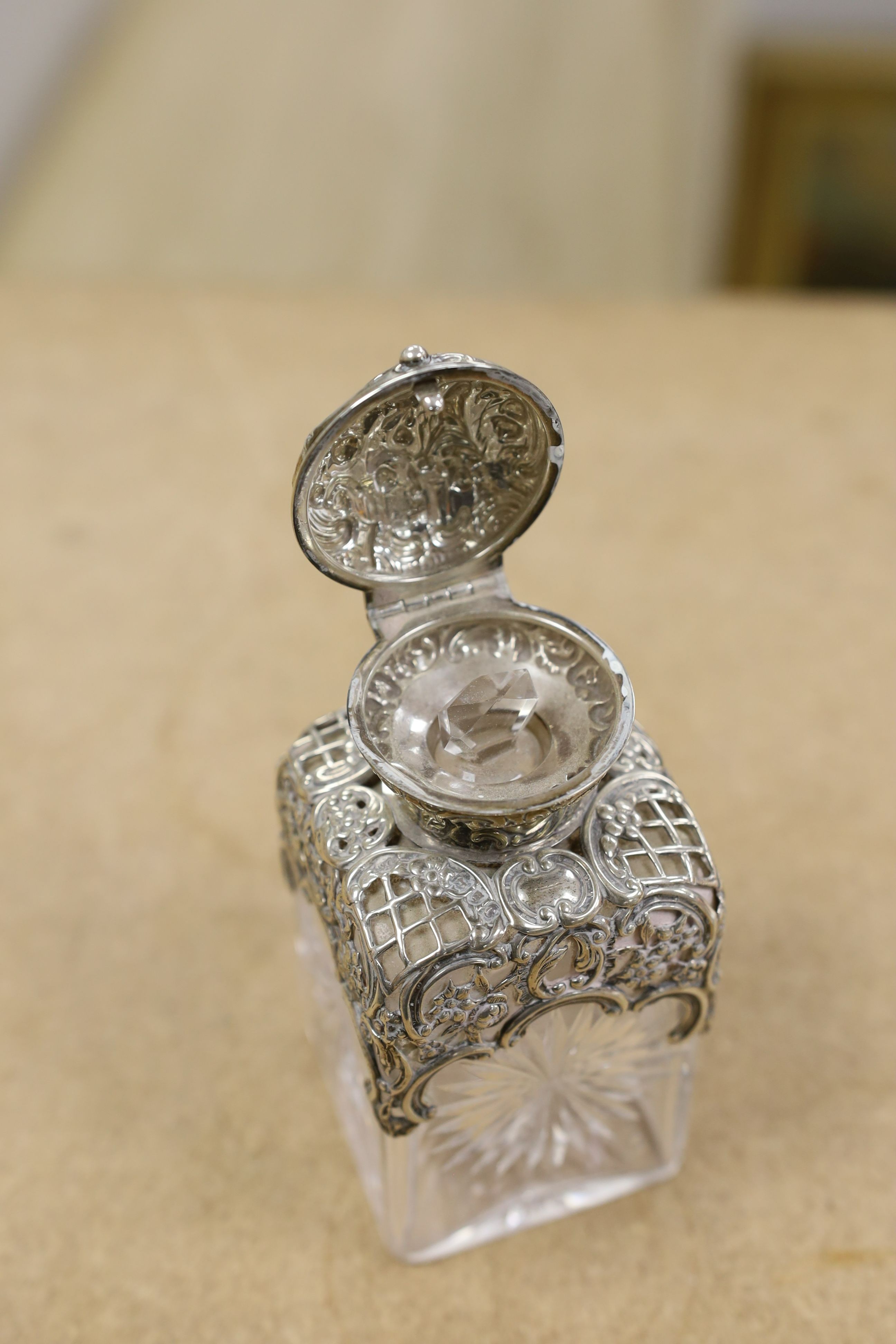 A pair of late Victorian repousse silver mounted cut glass scent bottles with stoppers, William Comyns, London, 1898, height 14.3cm.